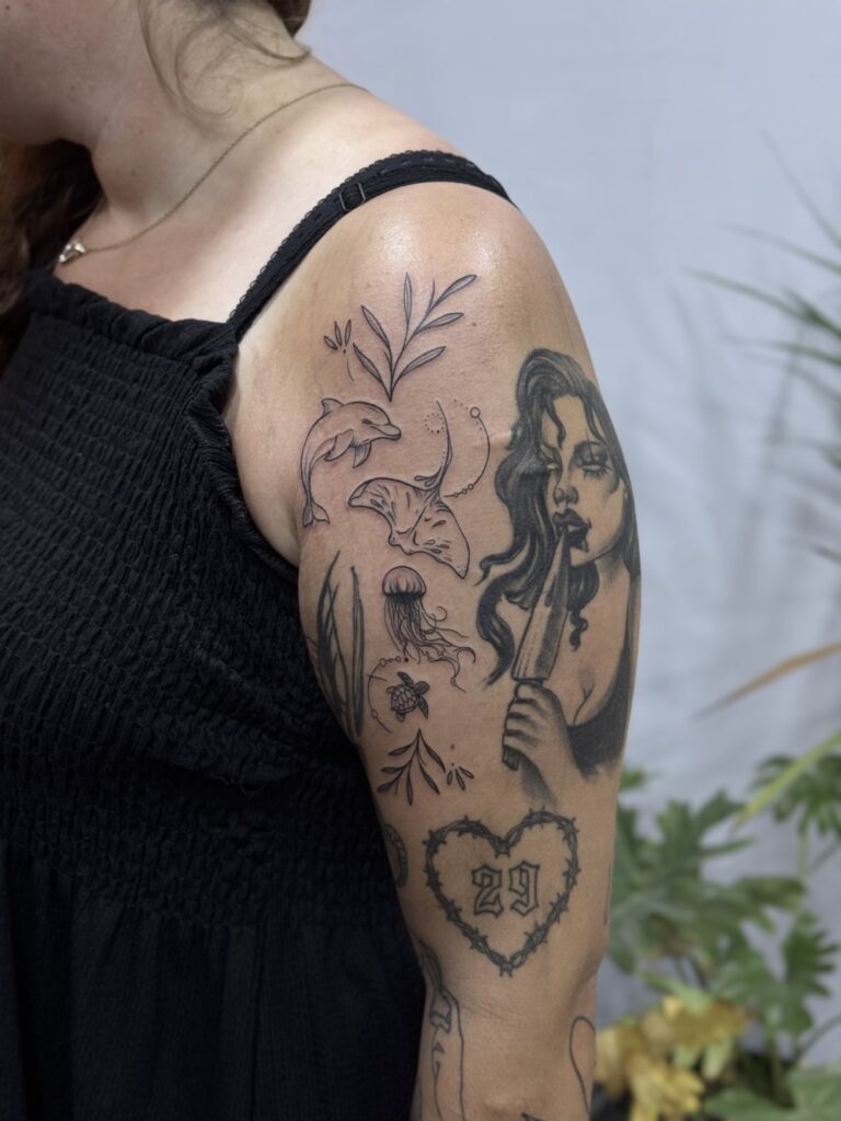 Black and grey patchwork tattoos on upper arm with portrait and roses