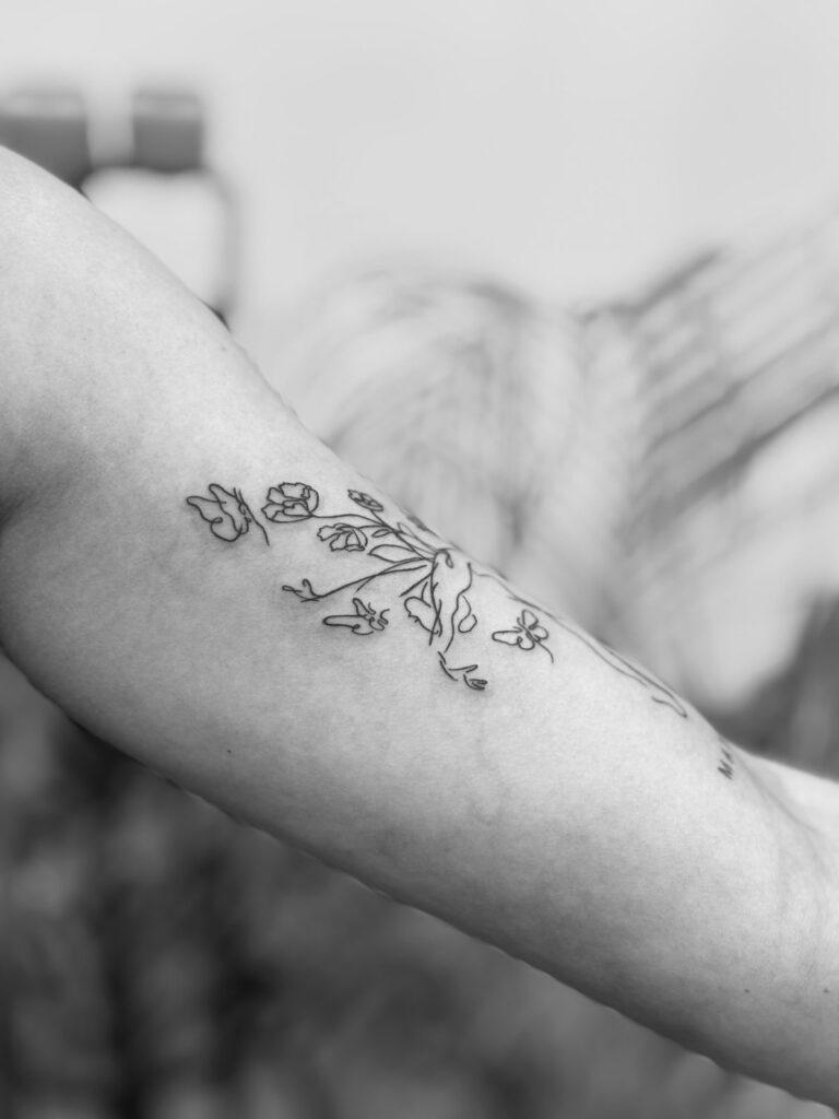 Fine line floral branch tattoo on forearm