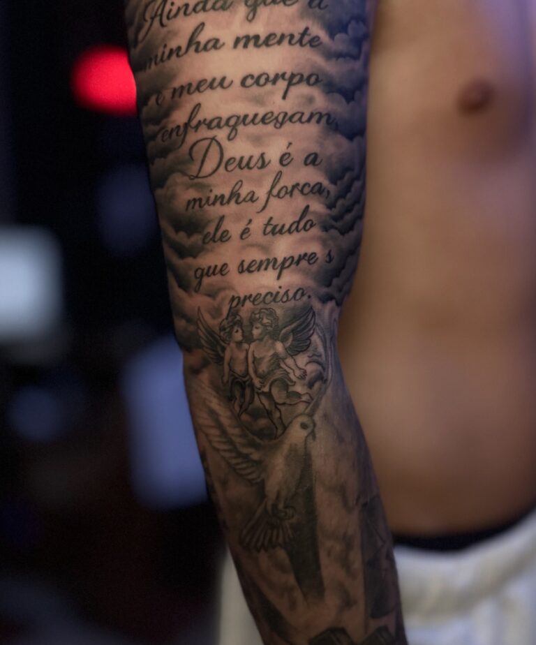 Script lettering and angel upper-arm sleeve tattoo – black and grey, Hurghada