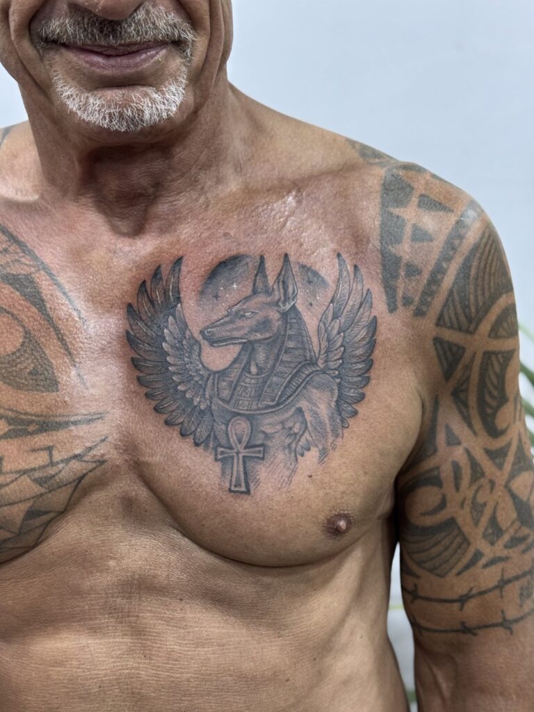 Egyptian winged scarab chest tattoo on a mature client – black and grey