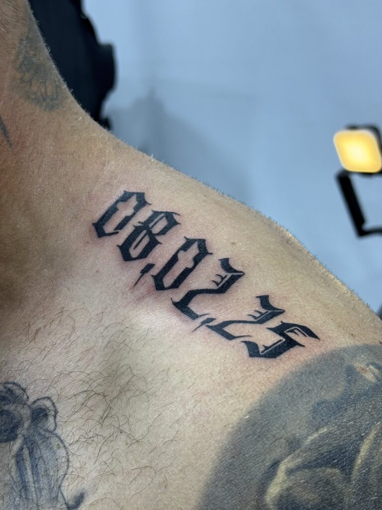 Date lettering 06.02.25 shoulder tattoo in blackletter script