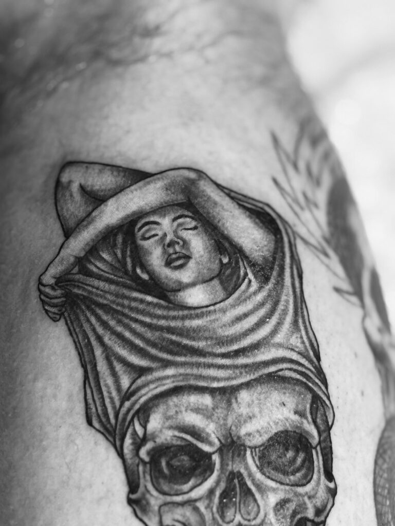 Pin-up woman over skull black and grey realism tattoo