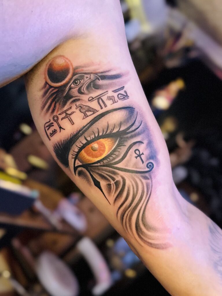 Eye of Ra and Egyptian symbols upper-arm tattoo with orange color realism